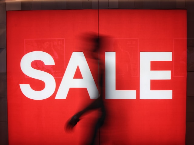 Silhouettes of shoppers in front of a sale sign at a Hong Kong mall.